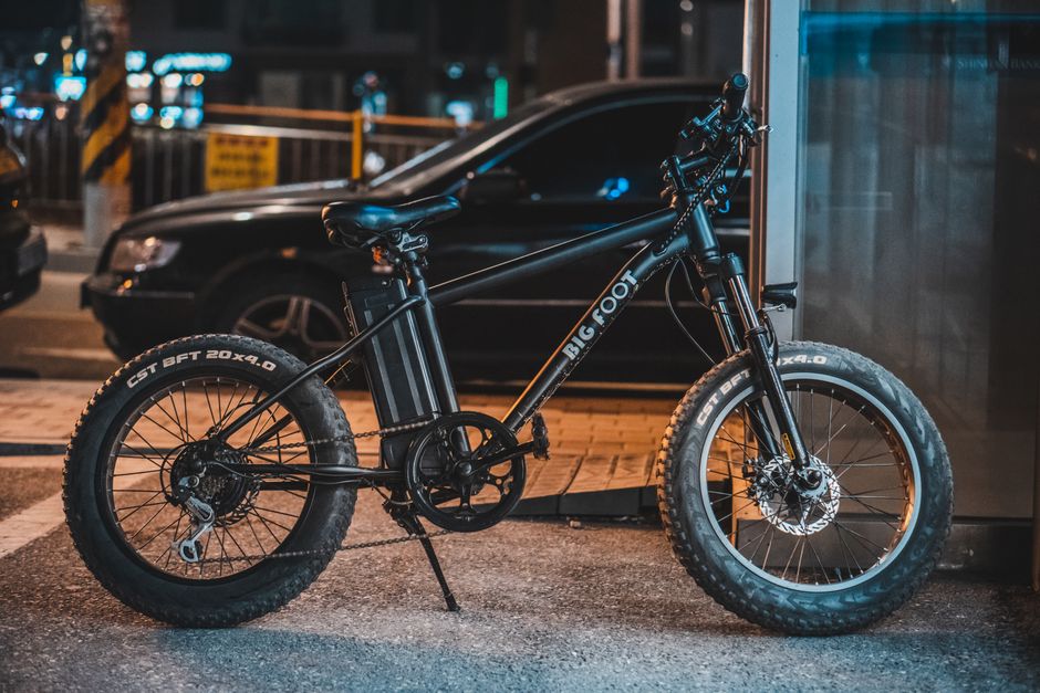 A modern e-bike parked by the sidewalk in an urban setting at night, showcasing technology.