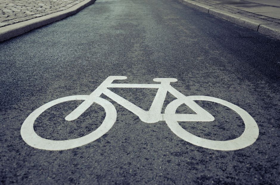 Close-up of a bicycle lane symbol painted on urban asphalt road surface.