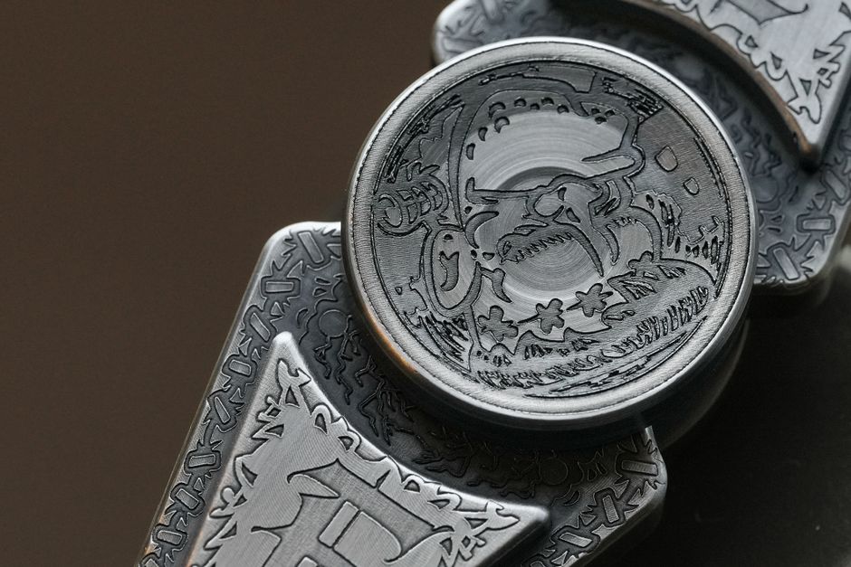 Close-up of bare metal pieces covered in fine engraved line work.