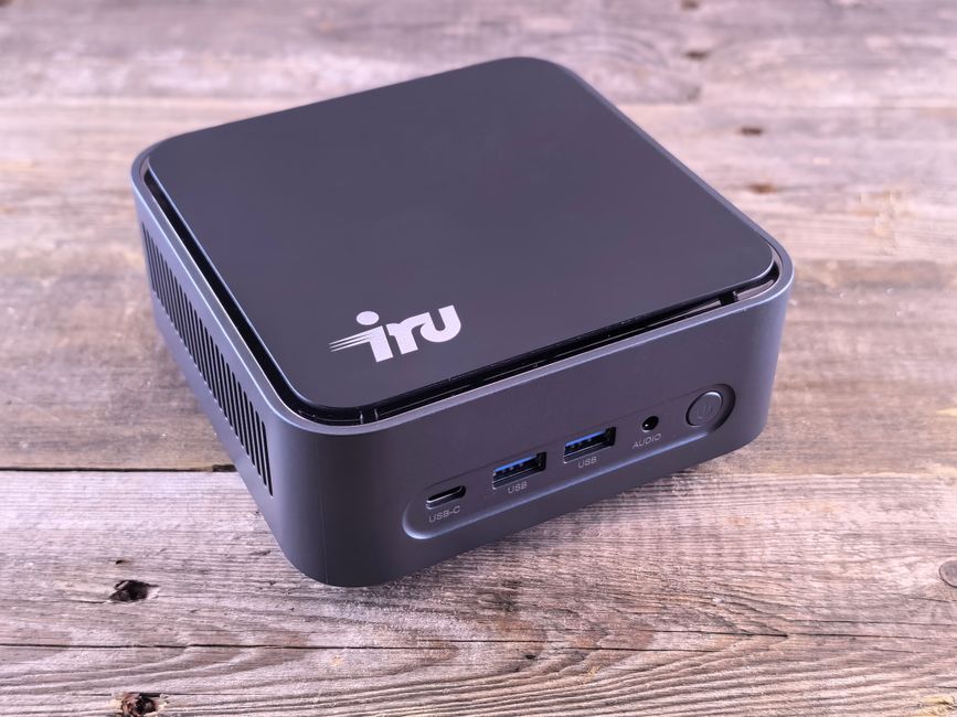 A small, sleek desktop computer featuring USB-C and various ports on a wooden surface.